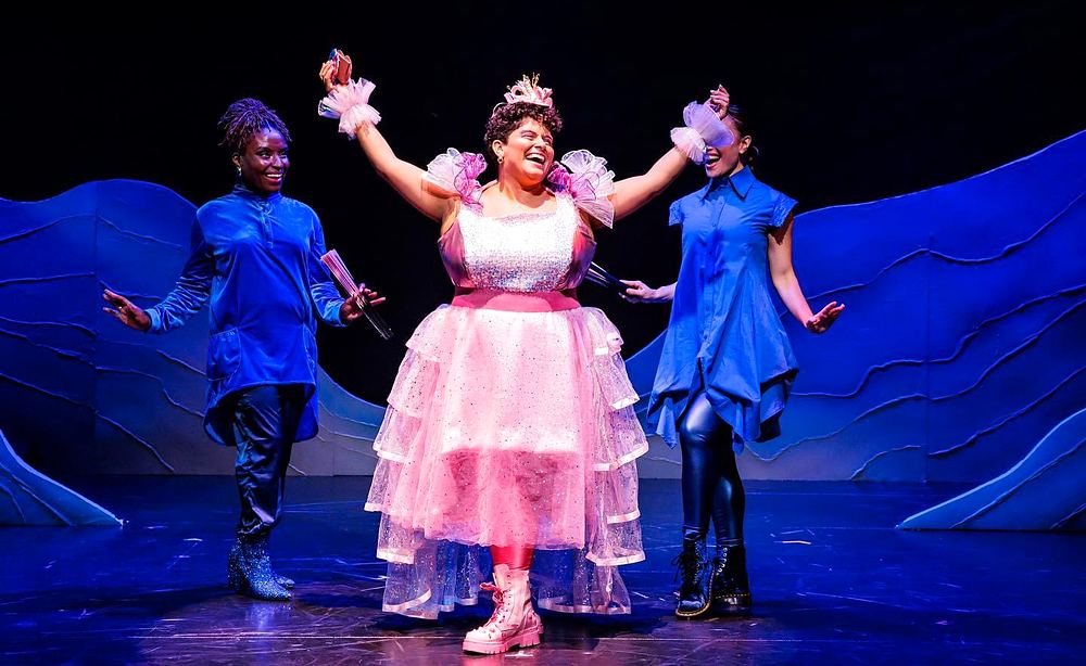 Woman in a pink tiered tulle gown and tiara between two dancers in blue, Spells of the Sea. Costume design by Cynthia Nordstrom