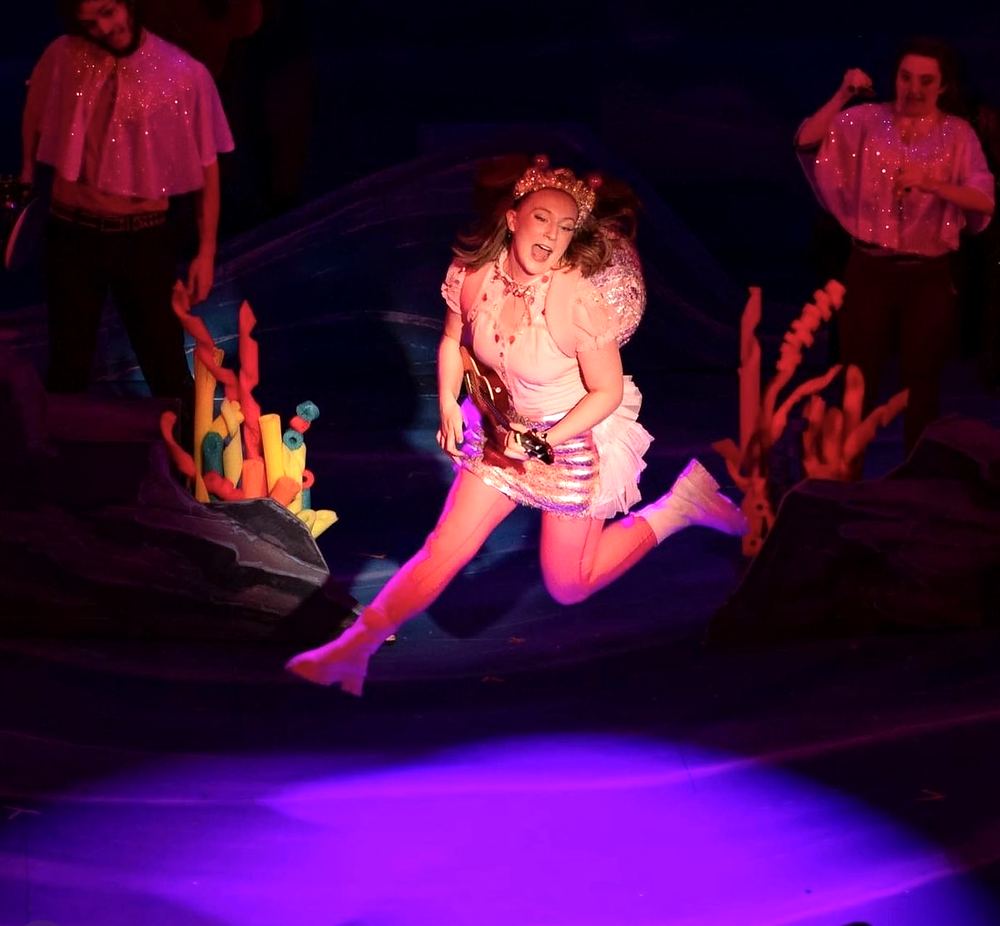 Princess in a white puffed dress leaping across a coral reef set, Spells of the Sea. Costume design by Cynthia Nordstrom