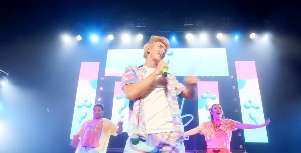 Stephen Sharer in a white outfit with dancers in bright colors under white stage lights, Stephen Sharer: Share the Love Tour. Co-costume design by Cynthia Nordstrom