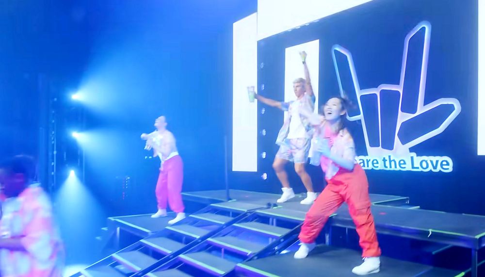 Stephen Sharer in white with dancers in pink and yellow on a blue lit stage, Stephen Sharer: Share the Love Tour. Co-costume design by Cynthia Nordstrom