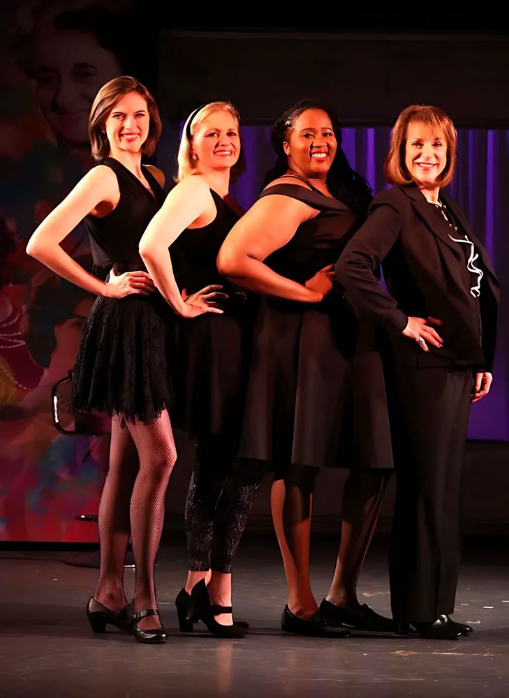 Four women in black dresses with silver jewelry on a collage backdrop stage, This One's for the Girls. Costume design by Cynthia Nordstrom