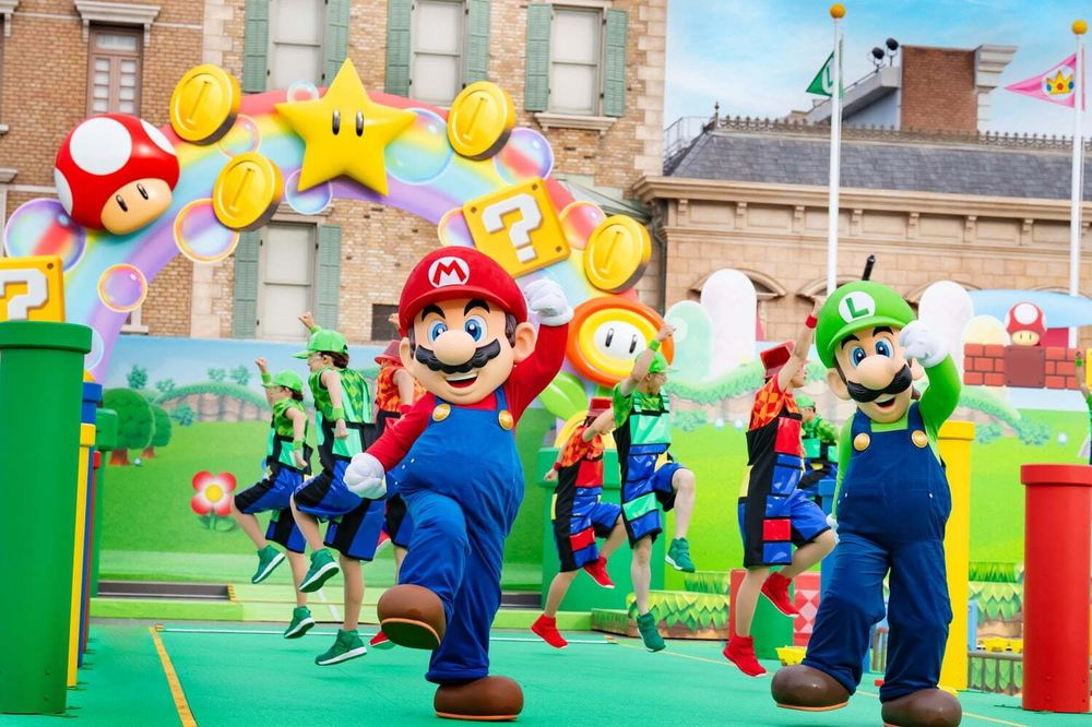 Mario, Luigi and dancers in green and red overalls before a mushroom arch, NO LIMIT! Parade, USJ. Costume design by Cynthia Nordstrom