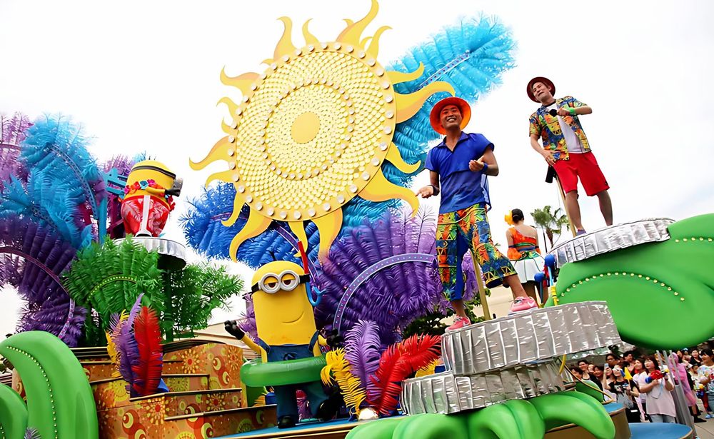 Parade float with a giant sun, blue feathers, Minions and performers, USJ anniversary shows. Costume design by Cynthia Nordstrom