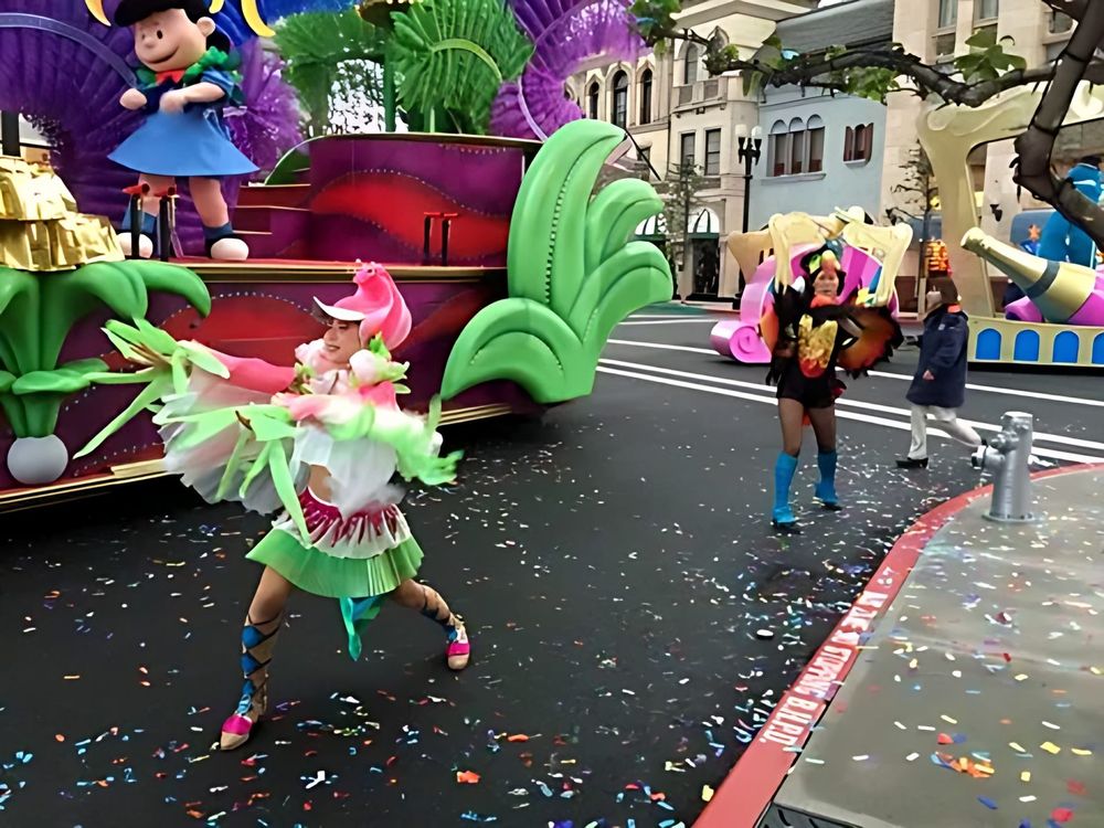Dancer in a green and pink petal costume before a Peanuts parade float, USJ anniversary shows. Costume design by Cynthia Nordstrom