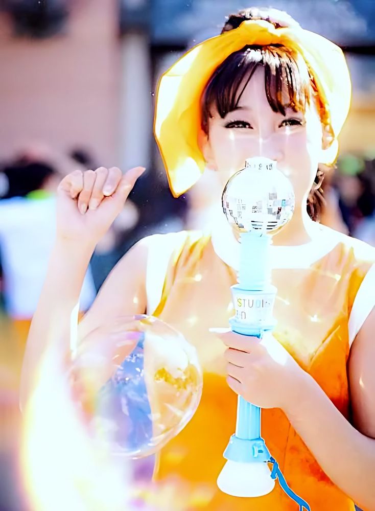 Performer in a yellow headband and orange top holding a bubble wand, NO LIMIT! Parade, USJ. Costume design by Cynthia Nordstrom