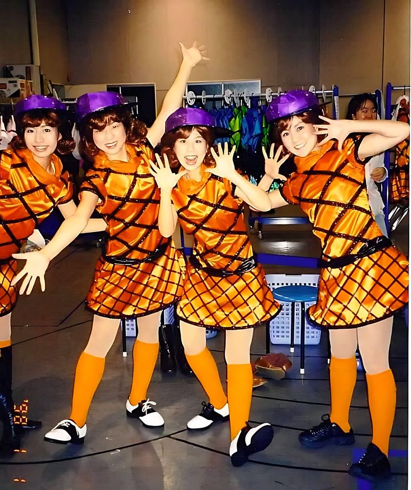 Dancers in orange and black argyle dresses, orange socks and purple caps, USJ anniversary shows. Costume design by Cynthia Nordstrom