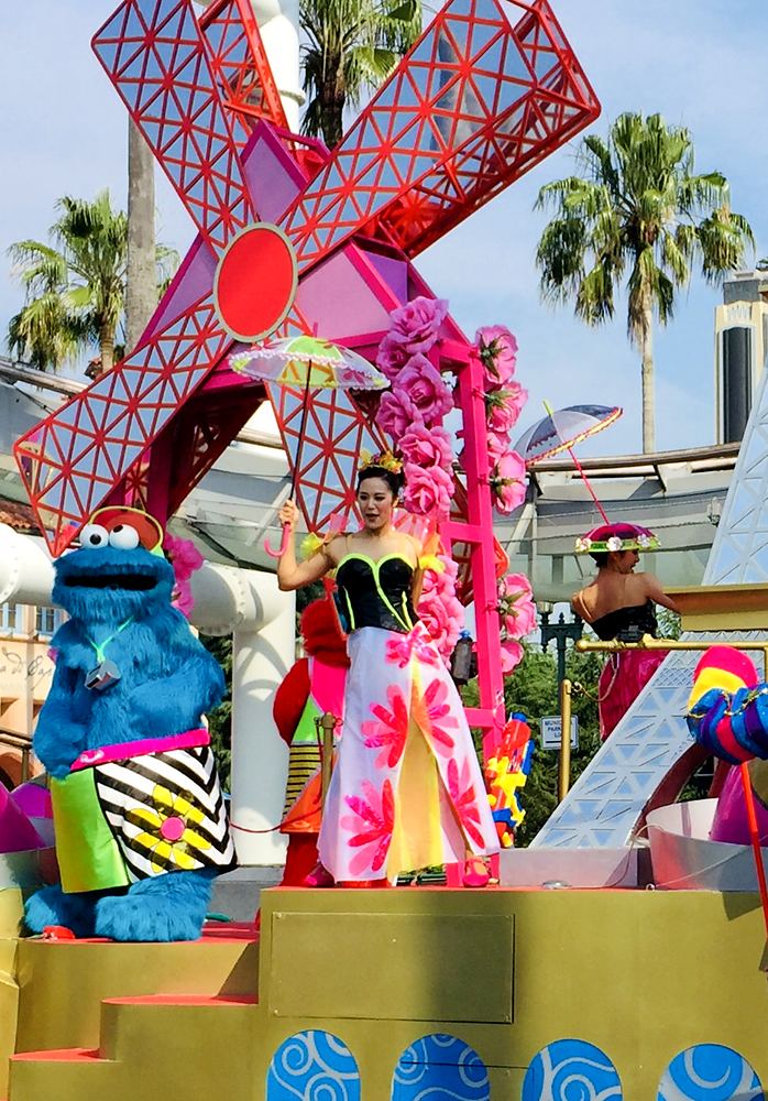 Cookie Monster and a singer in a colorful patterned gown on a float, USJ anniversary shows. Costume design by Cynthia Nordstrom