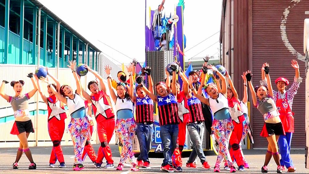 Parade dancers in bright patterned pants and tops cheering in a line, USJ anniversary shows. Costume design by Cynthia Nordstrom
