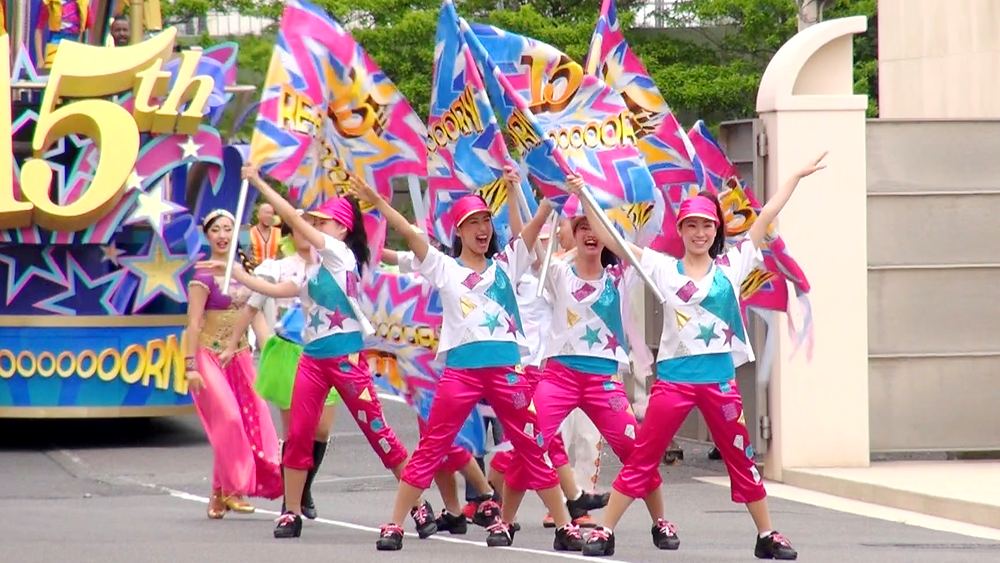 5th anniversary parade dancers in pink and white with big flags, USJ anniversary shows. Costume design by Cynthia Nordstrom