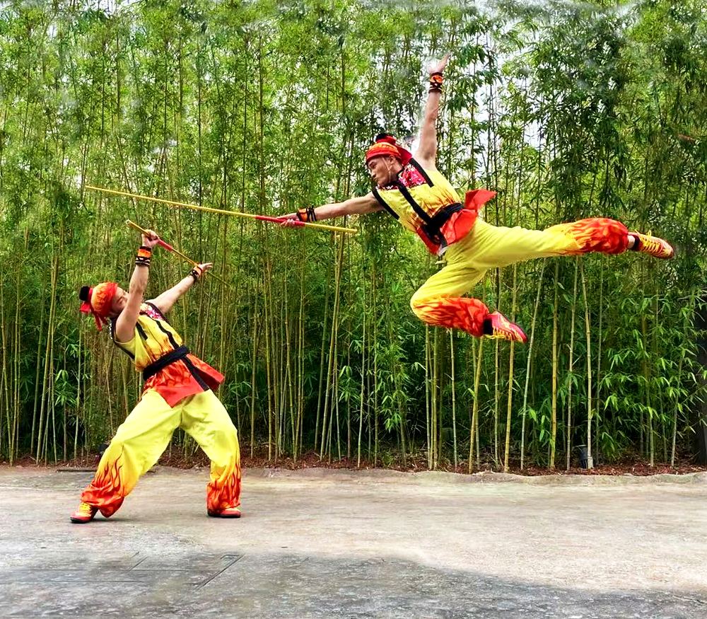 Two Monkey King wushu performers in yellow and red flame costumes leaping in a bamboo grove, Universal Beijing Resort. Costume design by Cynthia Nordstrom